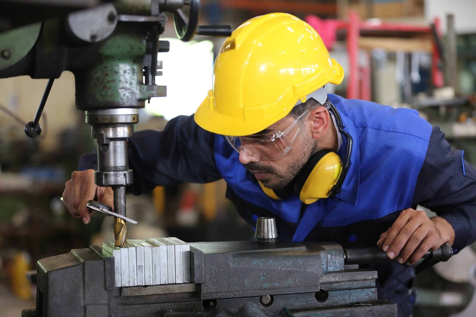 Worker at machine in factory, Metal industry worker at factory.