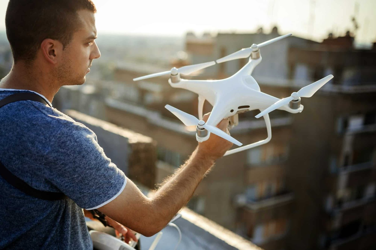 Young technician flying UAV drone with remote control on rooftop