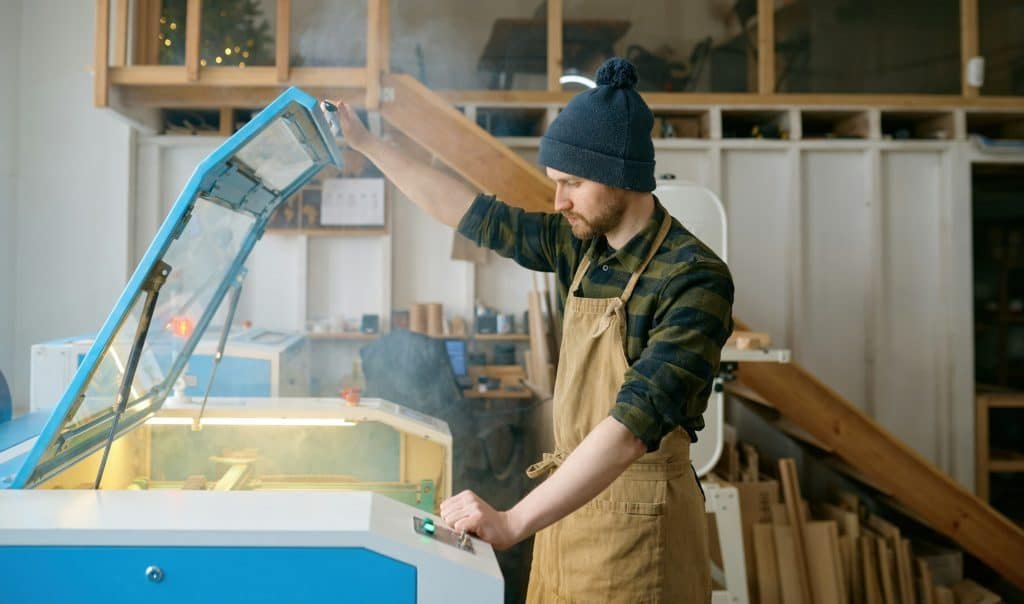 Man carpenter operating CNC laser machine in automated woodworking studio