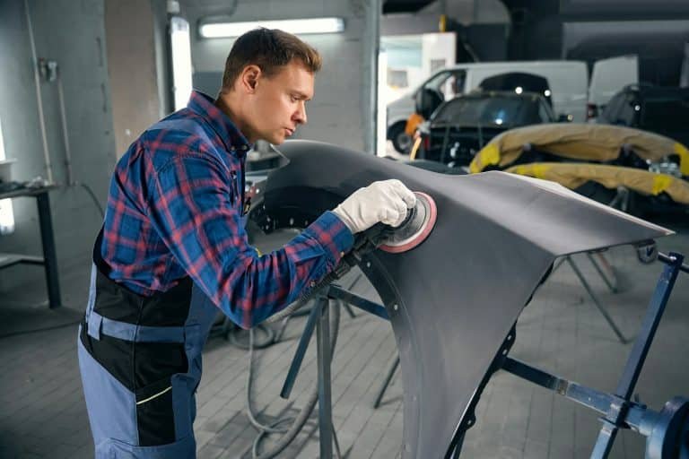 Man working with automobile part, polish surface