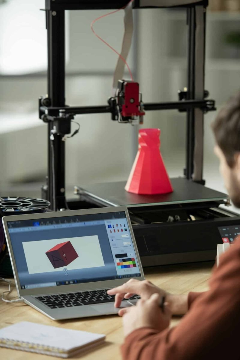 Young businessman sitting in front of laptop and working over new 3d model